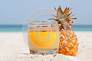 Glass of pineapple juice on a beach