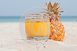 Glass of pineapple juice on a beach