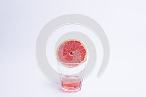 Glass of pink grapefruit juice over white background.