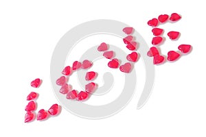 Glass pink hearts laid out in word Love. Diagonal, white isolated background