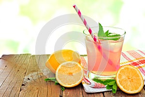 Glass of pink lemonade with mint and outdoors background