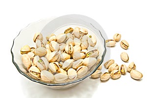 Glass plate with tasty pistachios on white photo