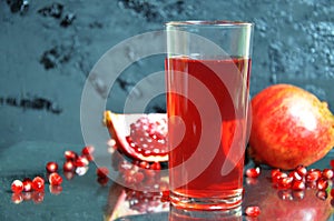 A glass of pomegranate juice with fresh pomegranate fruits on dark black background. Vitamins and minerals. Healthy