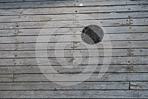 Glass porthole and wooden siding on an old sailing vessel