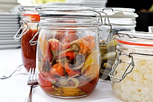 Glass preserving jars of pickled chillies, onions and gherkins o