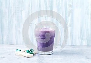 Glass of Protein Shake with milk and blueberries, Beta-alanine and L-Carnitine capsules in background. Sports bodybuilding nutriti