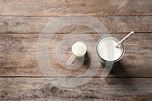 Glass of protein shake, scoop with powder and space for text on wooden background