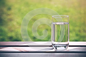 Glass of pure water on green natural background
