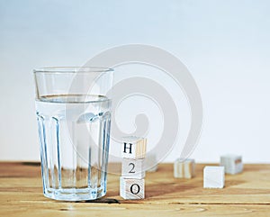 Glass of pure water with H2O formula in wooden blocks