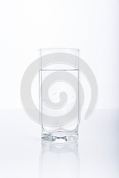 Glass of purified water on white background, reflection