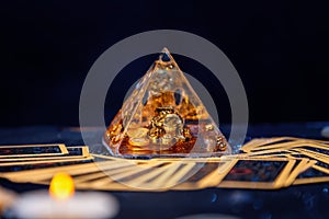 A glass pyramid with a Golden frog. Tarot cards are scattered on the table. Close-up. Copy space. The concept of divination, magic