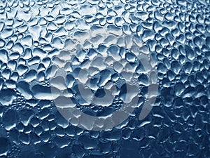Glass with raindrops on blue tone background