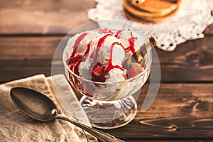 Glass ramekin with ice cream and spoon on table