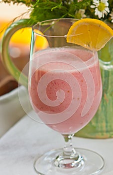 Glass of raspberry coconut smoothie with a slice of lemon