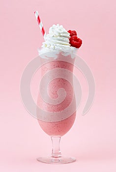 Glass of raspberry milkshake with whipped cream and fresh raspberries