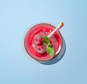 Glass of raspberry smoothie on blue background