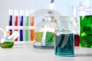 Glass reagent bottle and other glassware on table in chemistry laboratory