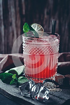 Glass of red alcoholic cocktail drink with ice, mint and lime. Summer refreshing drink