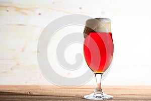 A glass of red beer on a wooden table, copy space