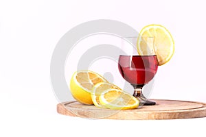 A glass with a red drink and lemon slices on a white background