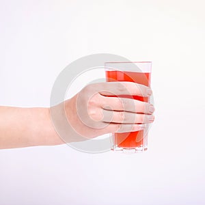 A glass with red grapefruit juice and a straw in her hand into a girl. Isolate on white background