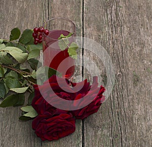 Glass of red juice, currant and bouquet of roses