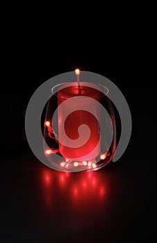 Glass with red lights and a candle inside, holiday season.
