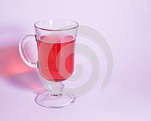 Glass with red liquid on a pink background