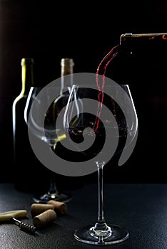 Glass of red and pink wine on a black background. Wine list menu. Close up of the power of glasses and bottles in low key