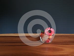 Glass of red potpourri flowers on table