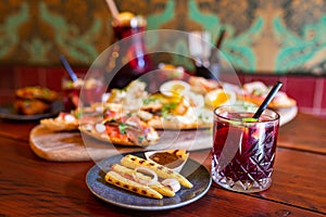 Glass of red Sangria on a table full of food with tapas platter in the background and an can of more Sangria