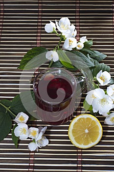 Glass of red tea, nearby lemon and flower