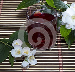 Glass of red tea on a rug with a flower