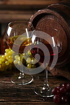 Glass of red and white wine with grapes on brown wooden background