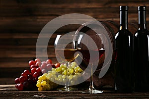 Glass of red and white wine with grapes on brown wooden background