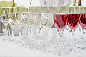 Glass of red and white wine on a table. Many glass wine in a row on white tablecloth.