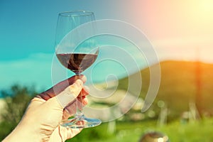 A glass with red wine on a background of a mountain landscape in the sun