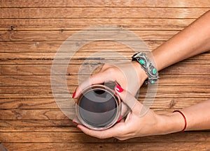 A glass of red wine in beautiful female hands on wooden background with copyspace