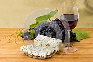 Glass of red wine, blue cheese and fresh blue grapes