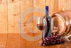 Glass of red wine bottle barrel and grapes