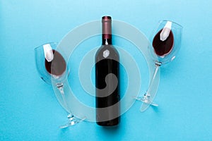 Glass of red wine and a bottle on colored table. Flat lay, top view wth copy space