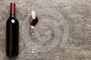 Glass of red wine and a bottle on colored table. Flat lay, top view wth copy space