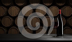 Glass of red wine with bottle on a rustic wooden table, wine barrels in the background