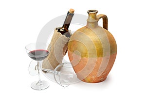 Glass with red wine, bottle and vintage amphora  on a white background