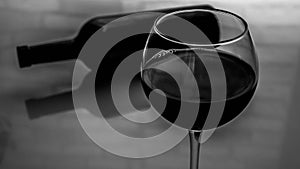 A glass of red wine with a bottle of wine. Black and white picture of wine in a glass