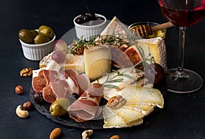 Glass of red wine and cheese plate with pieces moldy cheese, pro