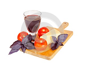 Glass of red wine, cheese, tomatoes and purple basil leaves isolated