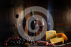 Glass of red wine cheeses grapesand barrel on brown wood
