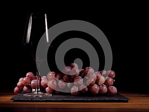 Glass of red wine and cluster of red grapes.