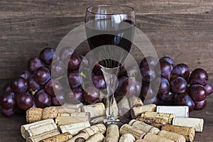 Glass of red wine, corks and grapes